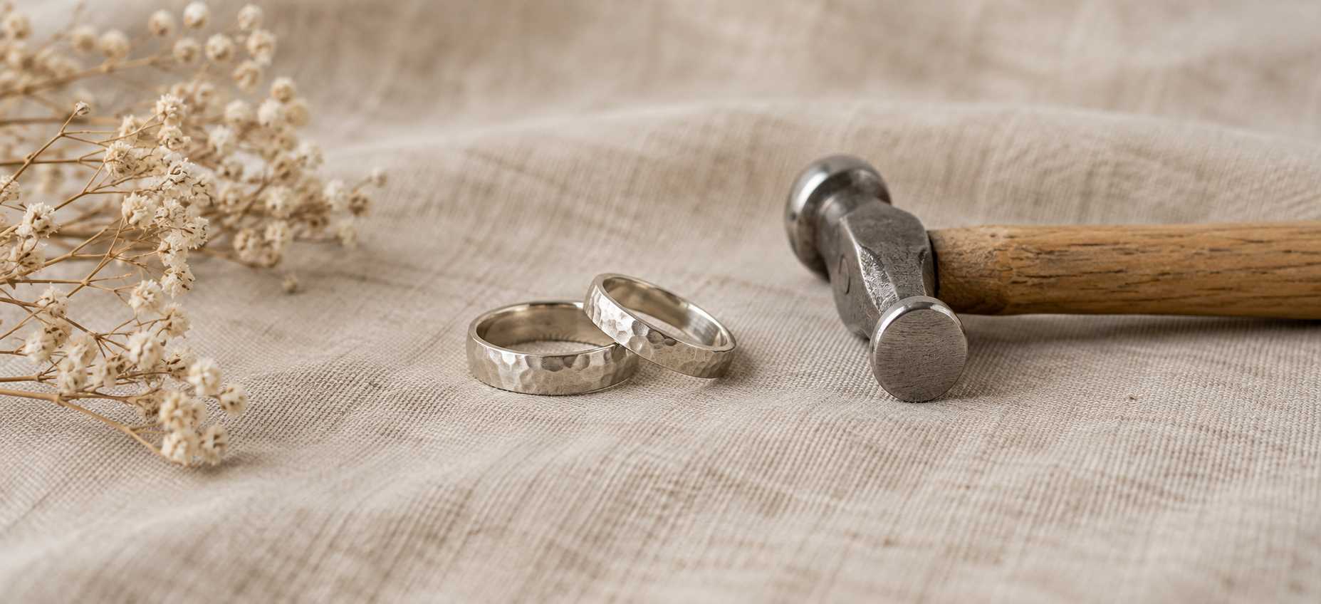 Two hammered rings and a small hammer resting on natural linen.